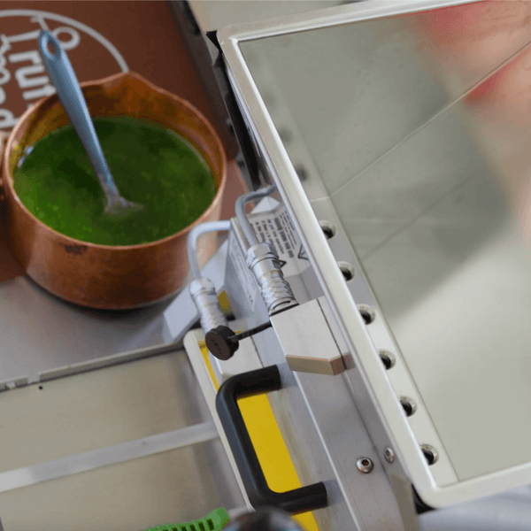 Green soup in a terracotta bowl with a spoon next to a metal toolbox.