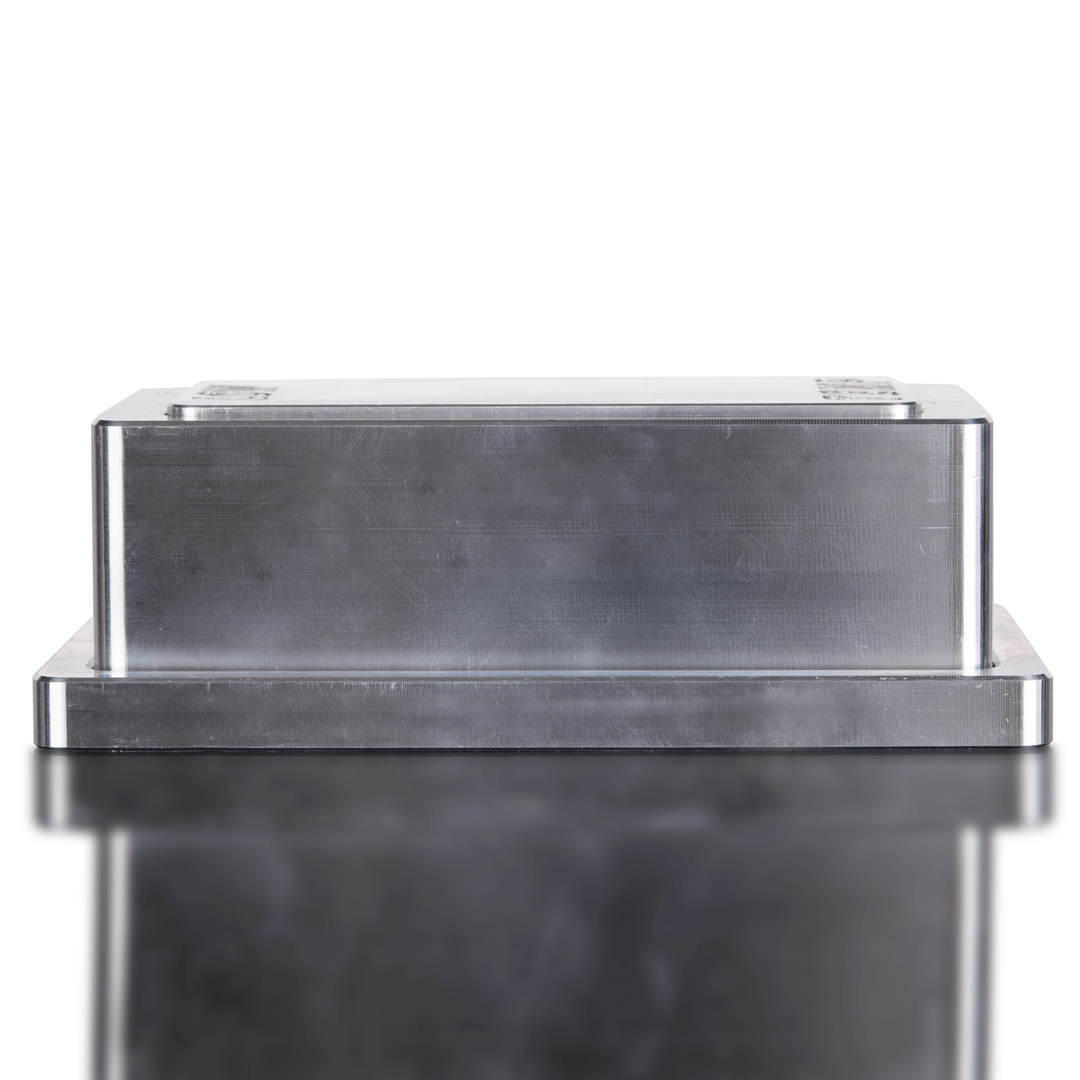 Metallic rectangular object on a reflective surface with a white background