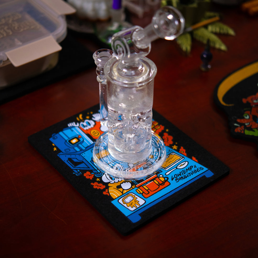 Clear glass smoking device on a colorful dab mat with a dark background