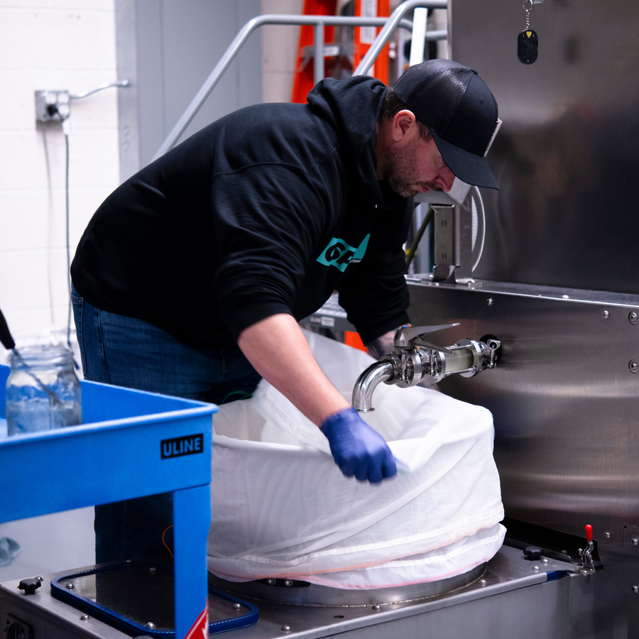 Man in black sweatshirt adding bubble hash bags to the nest recirculation tank 